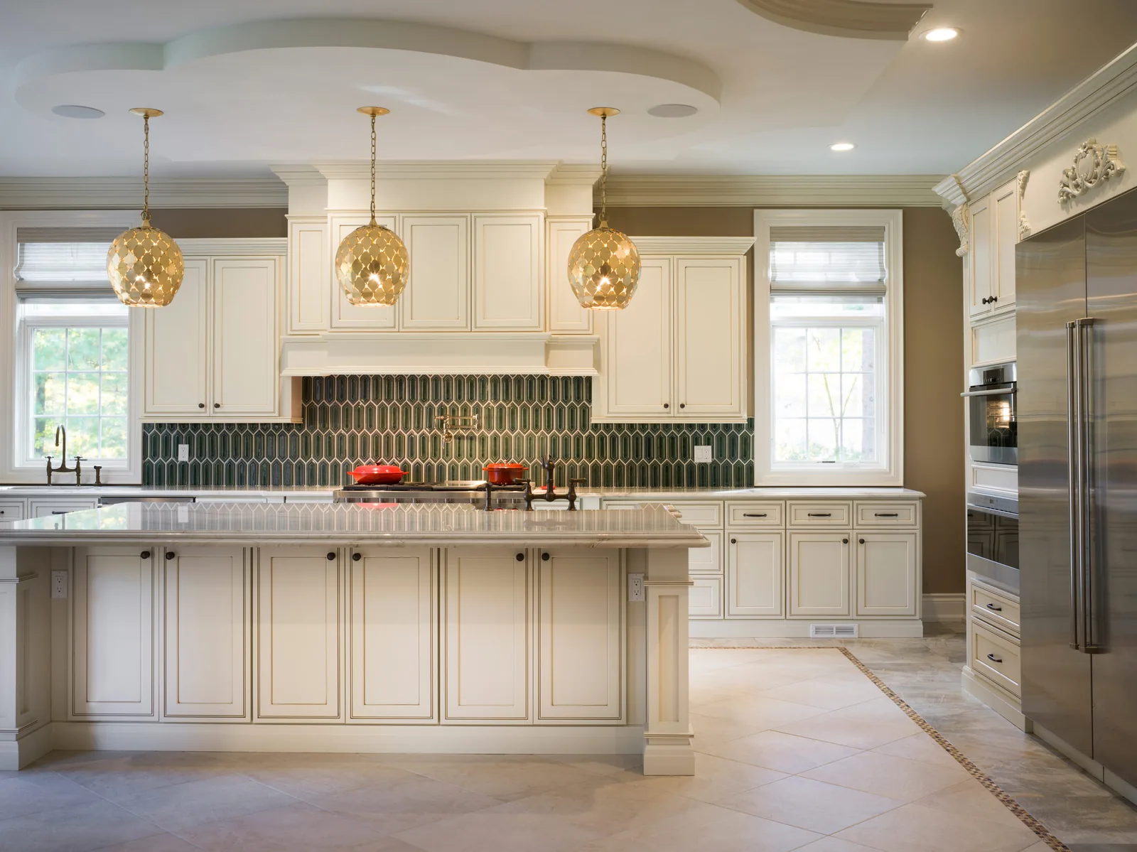 A pearl glazed kitchen with a range hood and a large island